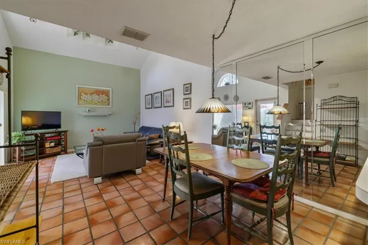 Tiled dining room featuring lofted ceiling