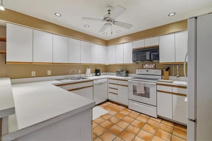 Kitchen featuring white cabinetry, white appliances, crown molding, light countertops, and recessed lighting