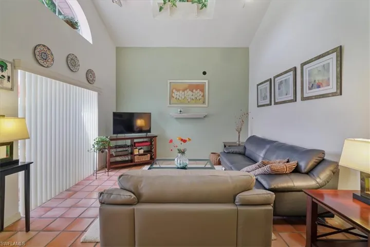 Tiled living area featuring high vaulted ceiling