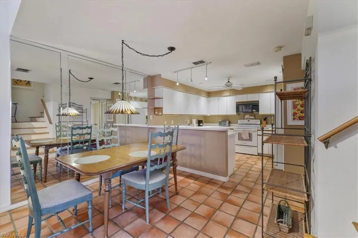 Kitchen featuring white cabinets, light countertops, a peninsula, white electric range oven, and black microwave