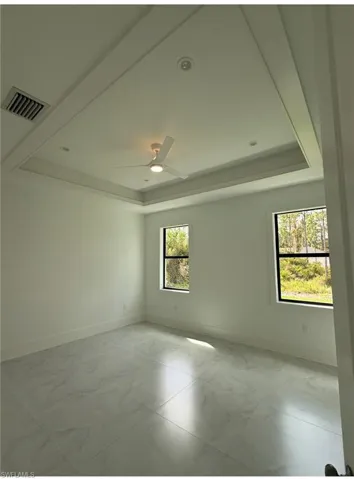 Empty room with a raised ceiling and light marble finish flooring