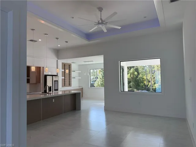 Kitchen featuring modern cabinets, a tray ceiling, open shelves, and hanging light fixtures