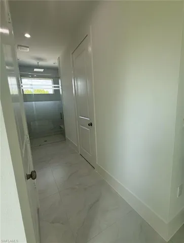 Corridor with light marble finish flooring and recessed lighting