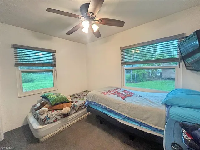 Carpeted bedroom featuring multiple windows and ceiling fan