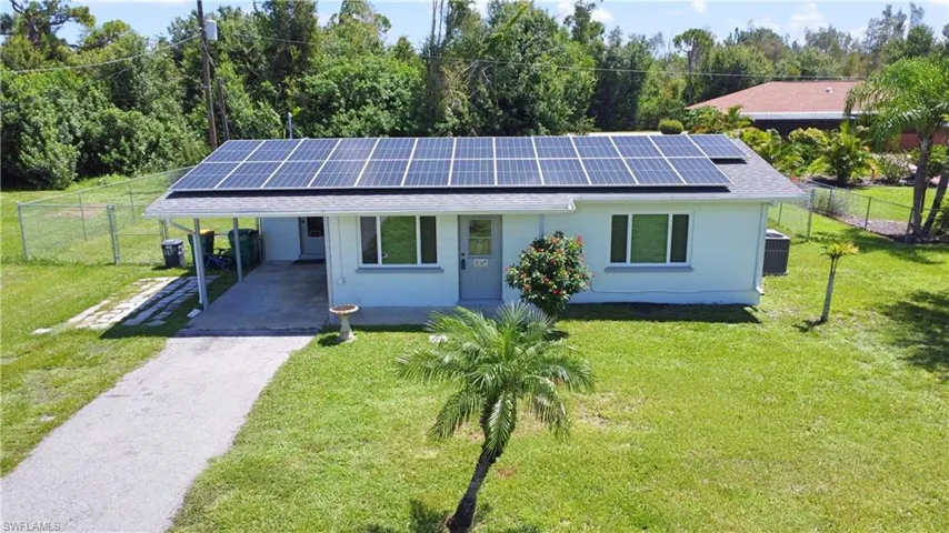Ranch-style home with solar panels, a carport, and a front yard