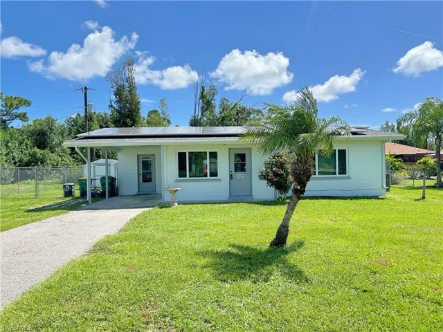Single story home featuring a front lawn and solar panels