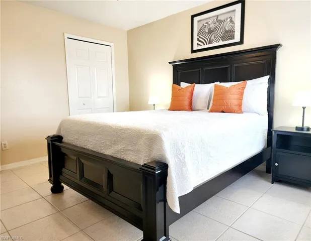 Bedroom with light tile patterned floors, a closet, and baseboards