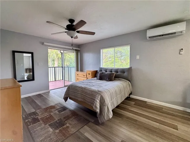Bedroom featuring access to exterior, wood finished floors, ceiling fan, a wall unit AC, and a textured wall