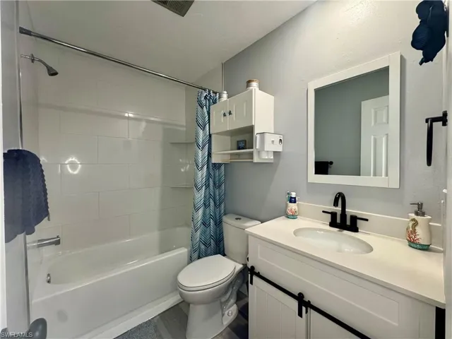 Bathroom featuring shower / bath combination with curtain and vanity