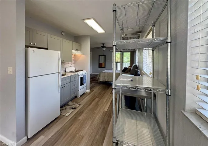 Kitchen featuring white appliances, light countertops, gray cabinetry, dark wood finished floors, and backsplash