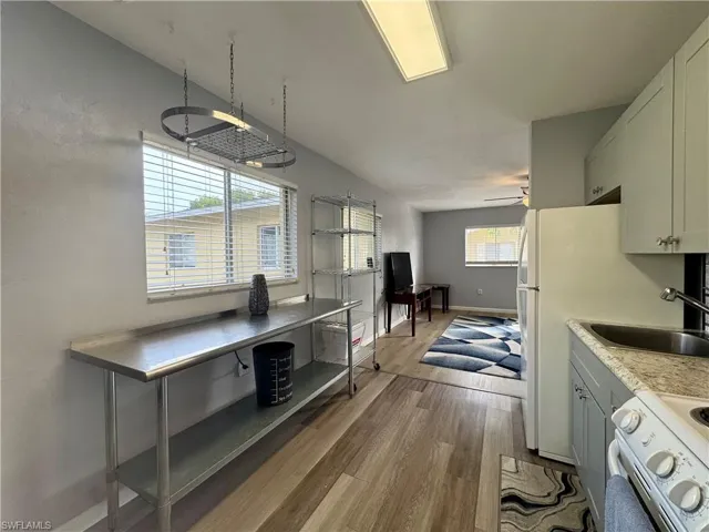 Kitchen featuring white range with electric stovetop, dark wood-style flooring, light countertops, gray cabinetry, and a ceiling fan