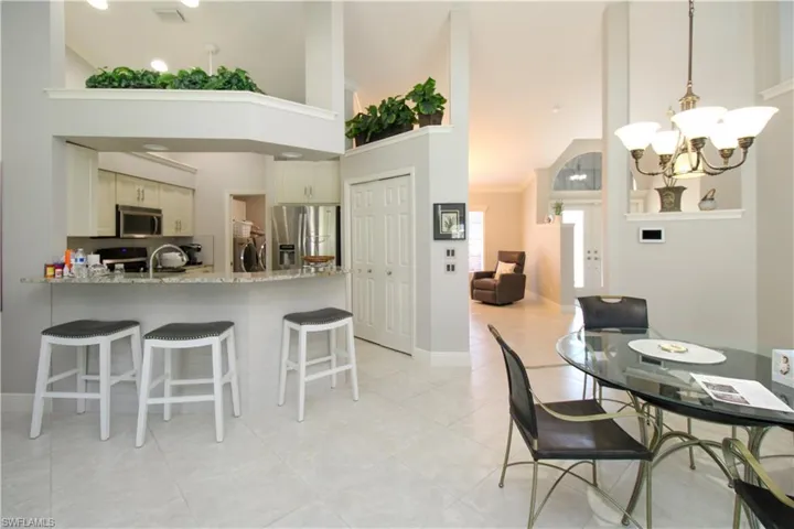 Dining area with visible vents, washer and clothes dryer, a towering ceiling, light tile patterned flooring, and a notable chandelier