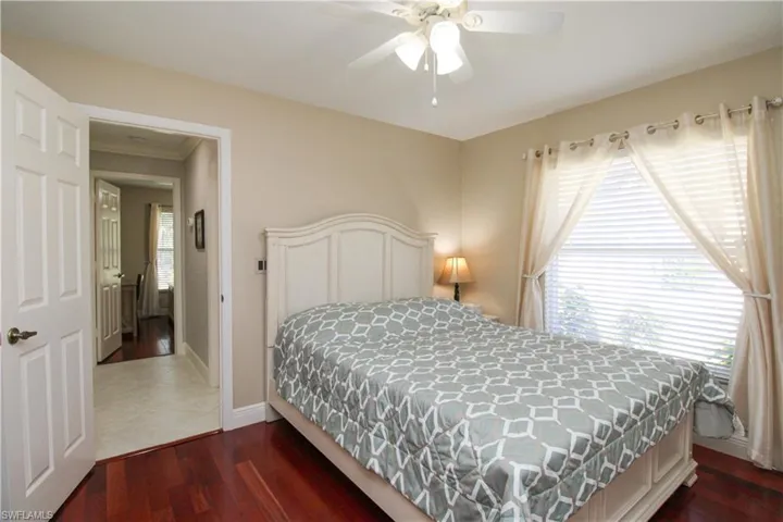 Bedroom with dark wood finished floors, baseboards, and ceiling fan