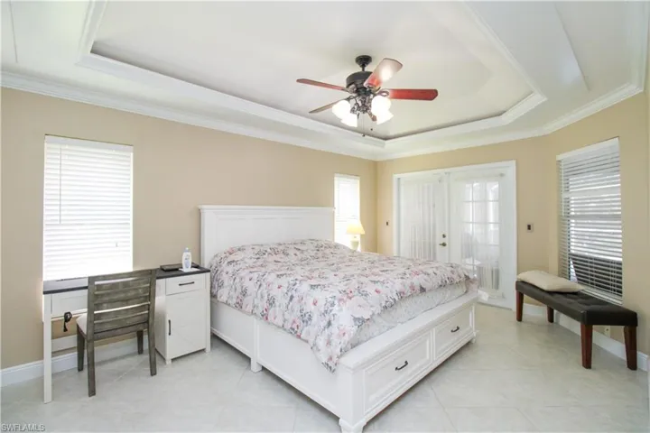 Bedroom with a raised ceiling, ceiling fan, and crown molding