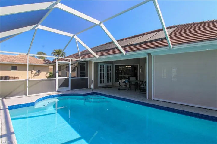 Pool with glass enclosure, a patio, and french doors