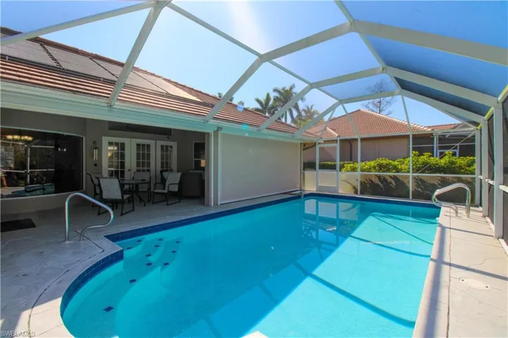 Pool featuring glass enclosure, a patio area, and french doors
