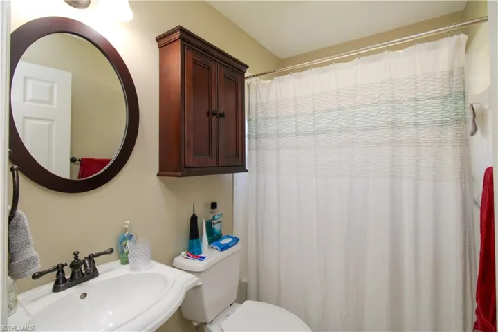 Bathroom featuring a sink, curtained shower, and toilet