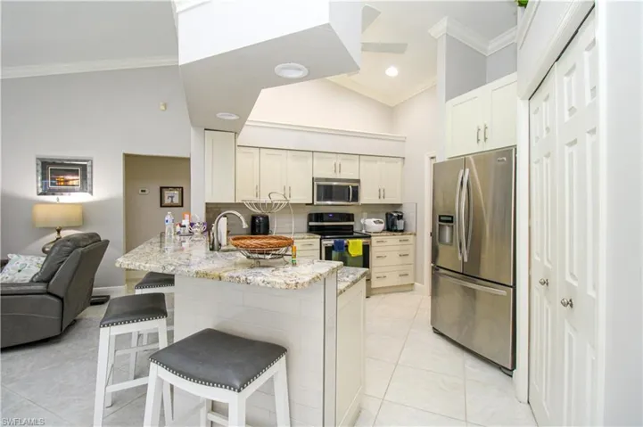 Kitchen featuring a peninsula, ornamental molding, open floor plan, and stainless steel appliances