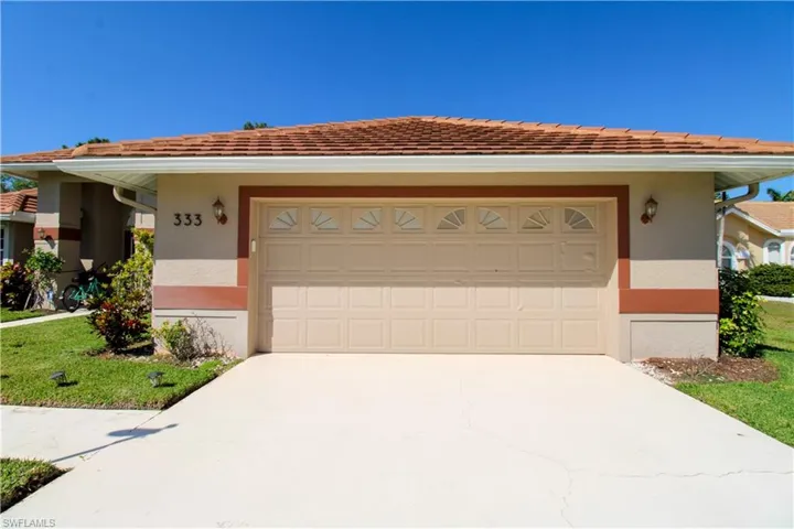 View of front of home with concrete driveway, an attached garage, a front yard, and stucco siding