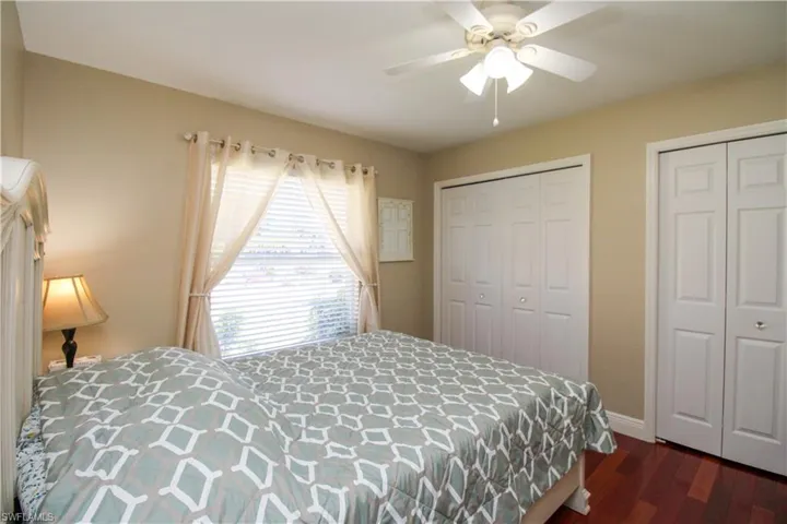 Bedroom with two closets, ceiling fan, and dark wood-style flooring