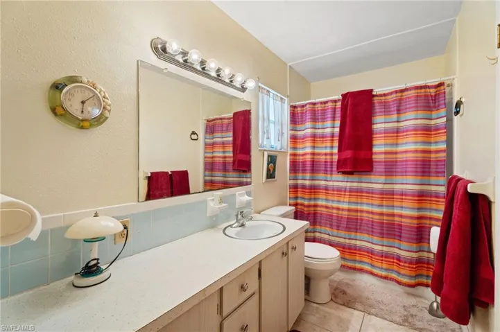 Bathroom featuring tasteful backsplash, tile patterned flooring, vanity, and curtained Shower/Bath combination.