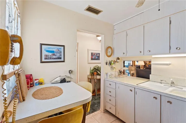 Kitchen featuring a sink, light countertops, Pass-through, and white cabinetry
