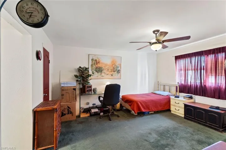 Carpeted bedroom featuring a ceiling fan and an office area