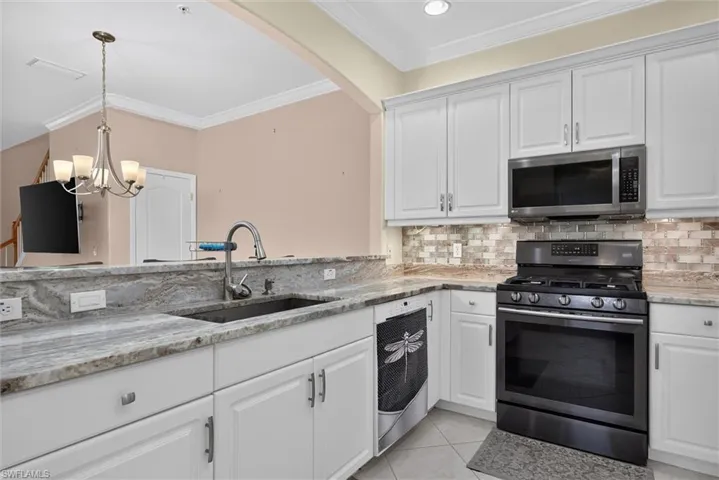 White shaker cabinetry in a kitchen featuring stone countertops, a stainless steel gas range, and an over-the-range microwave