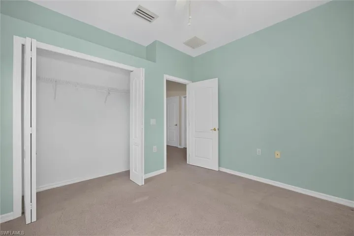 Carpeted interior space featuring a bi-fold closet, recessed ceiling vent, and a ceiling fan