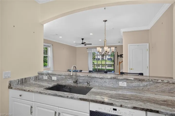 Kitchen pass-through featuring stone countertops with an undermount sink and a gooseneck faucet