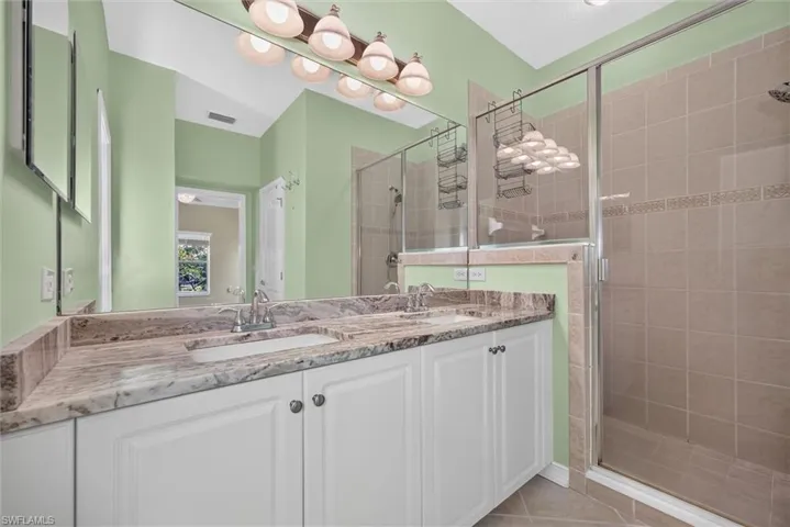 Dual vanity with undermount sinks and extensive countertop space, complemented by a large wall-mounted mirror and integrated lighting fixture