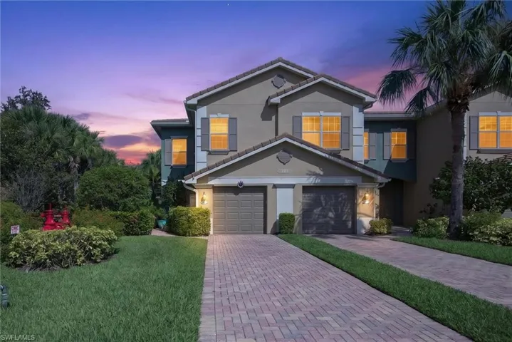 Multi-level stucco exterior featuring a two-car garage with individual doors, a terracotta-style tile roof, and decorative window shutters