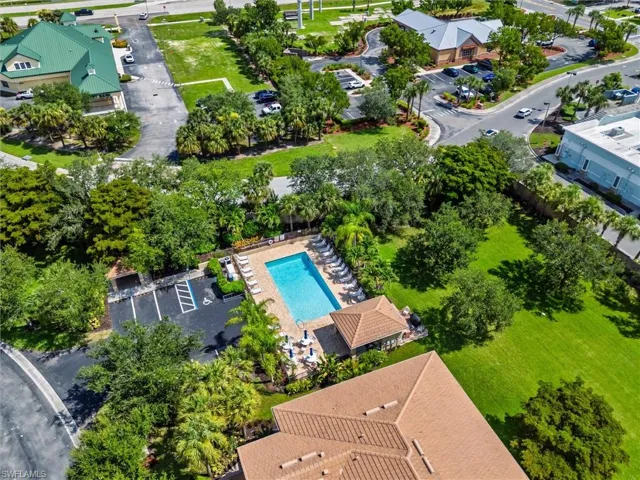 Outdoor swimming pool with surrounding lounge seating, a tiled roof cabana, and adjacent paved parking