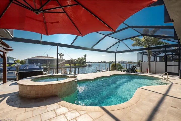 View of pool with a lanai, a pool with connected hot tub, a sunroom, a dock, and a water view