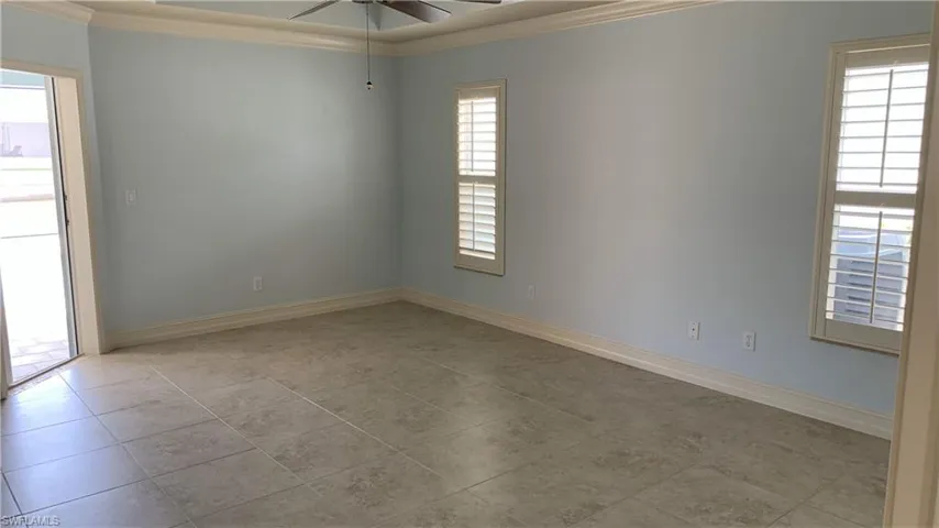 Spare room with crown molding, a ceiling fan, and light tile patterned floors