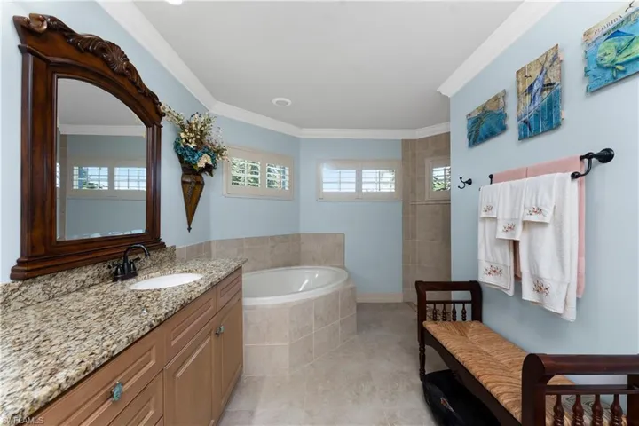 Bathroom with vanity, a garden tub, crown molding, a walk in shower, and light tile patterned flooring
