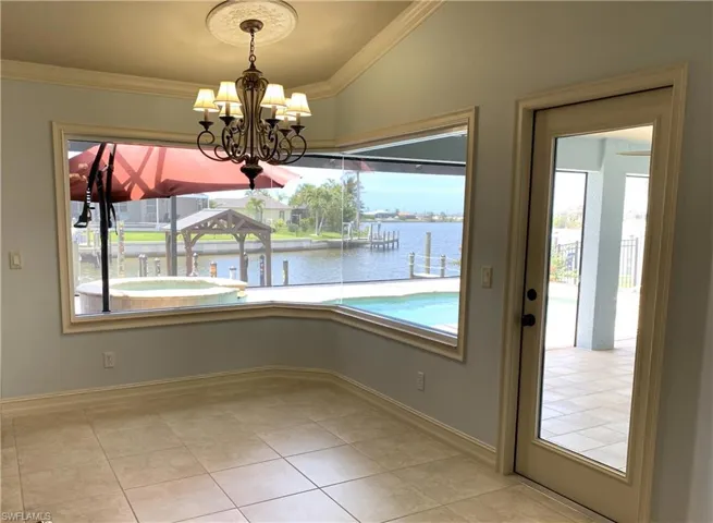 Unfurnished dining area with a water view, crown molding, light tile patterned floors, and a chandelier
