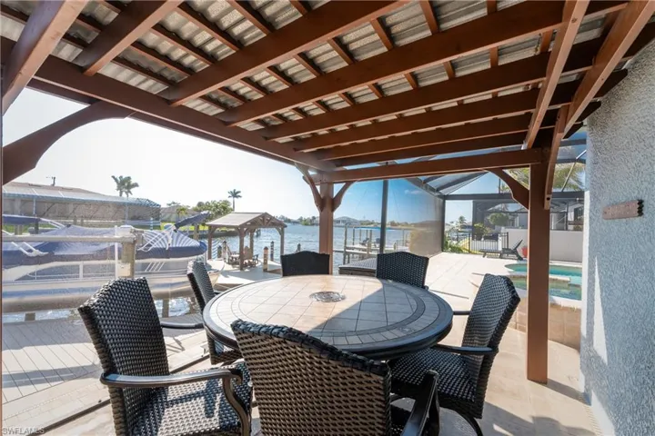 View of patio / terrace with a water view, a jacuzzi, a gazebo, glass enclosure, and boat lift