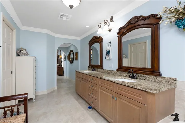 Full bathroom with double vanity, ornamental molding, and light tile patterned flooring