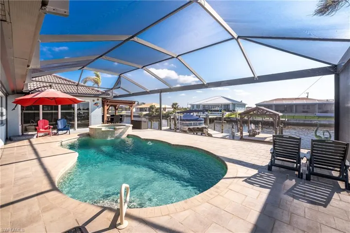 View of swimming pool featuring a patio, a lanai, boat lift, a sunroom, and a pool with connected hot tub