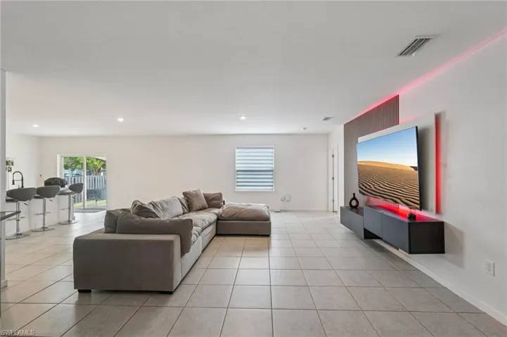 Living room with plenty of natural light, light tile patterned floors, and recessed lighting
