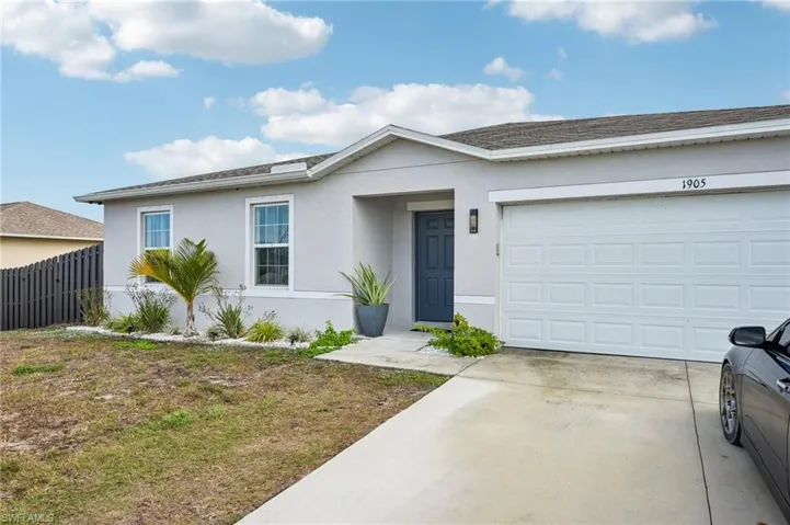 Single story home with stucco siding, driveway, and a garage