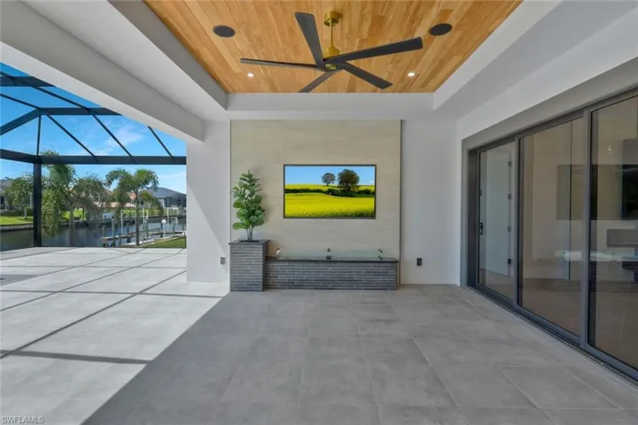 View of patio with ceiling fan, a sunroom, and glass enclosure