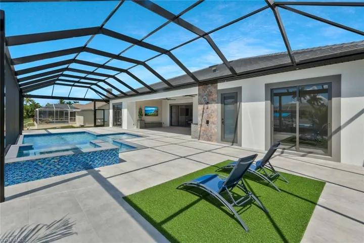 View of pool featuring a sunroom, a lanai, a patio area, a pool with connected hot tub, and ceiling fan
