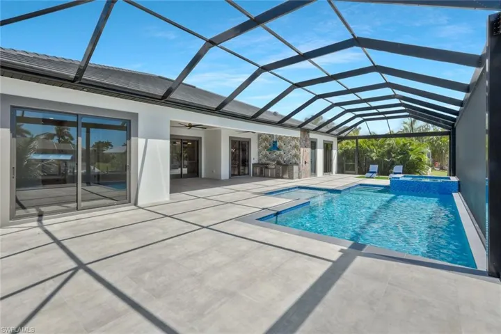 View of swimming pool featuring a sunroom, glass enclosure, a pool with connected hot tub, a ceiling fan, and a patio area