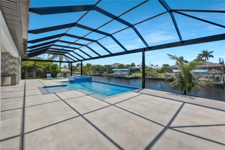View of swimming pool with a sunroom, a lanai, a water view, a pool with connected hot tub, and a patio