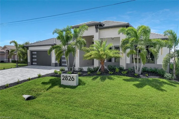 View of front of house featuring stucco siding, a front yard, decorative driveway, a tiled roof, and a garage