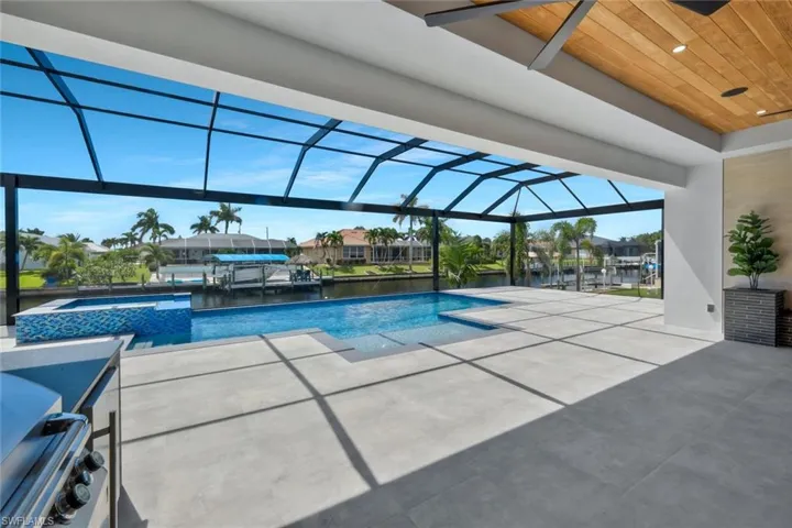 View of swimming pool featuring a water view, glass enclosure, a sunroom, a patio, and a pool with connected hot tub