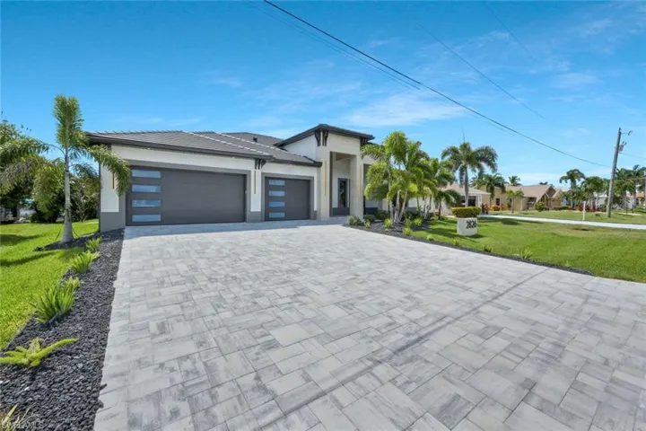 View of front of home with a front lawn, a garage, decorative driveway, and stucco siding