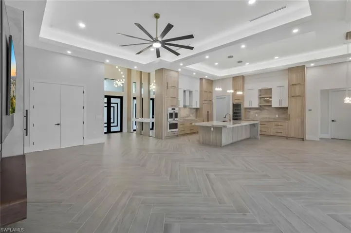 Living area with a tray ceiling, recessed lighting, and a ceiling fan